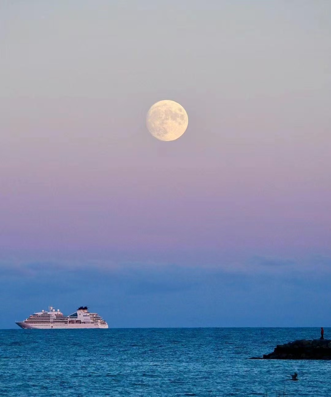 Full moon over the sea with a passing cruise ship